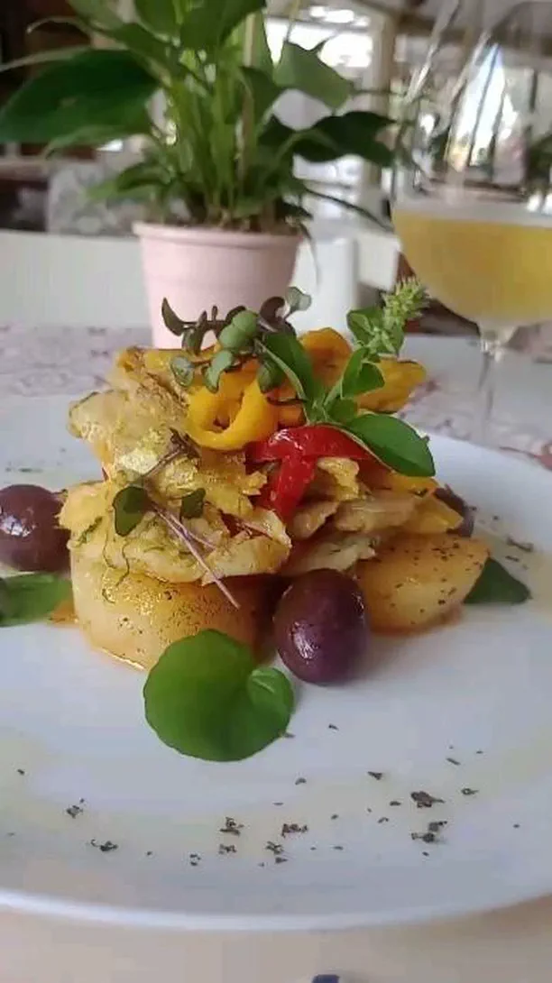 Lascas de bacalhau sobre batatas, com azeitonas e pimentões