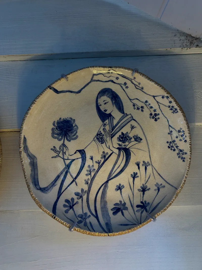 Prato de cerâmica pintado à mão em azul e branco, com uma figura feminina de quimono